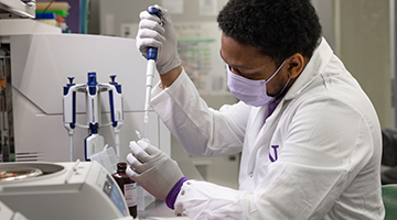 Man in lab inserting pipette into vial